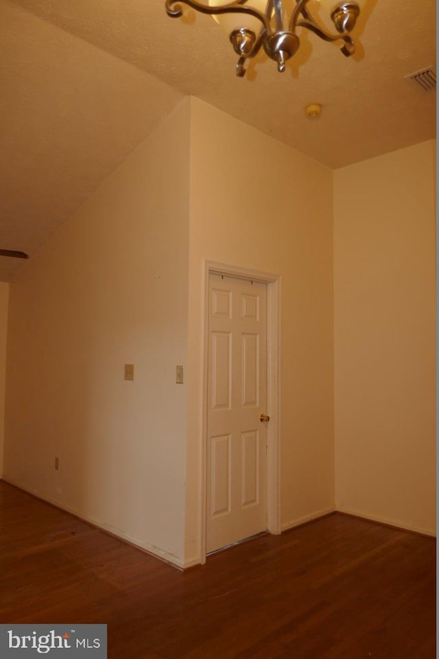 additional living space featuring vaulted ceiling, an inviting chandelier, and hardwood / wood-style flooring