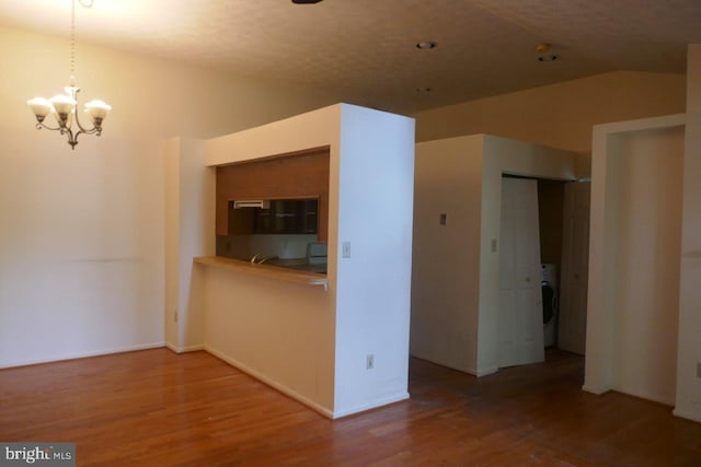 kitchen with a notable chandelier, lofted ceiling, pendant lighting, and hardwood / wood-style flooring