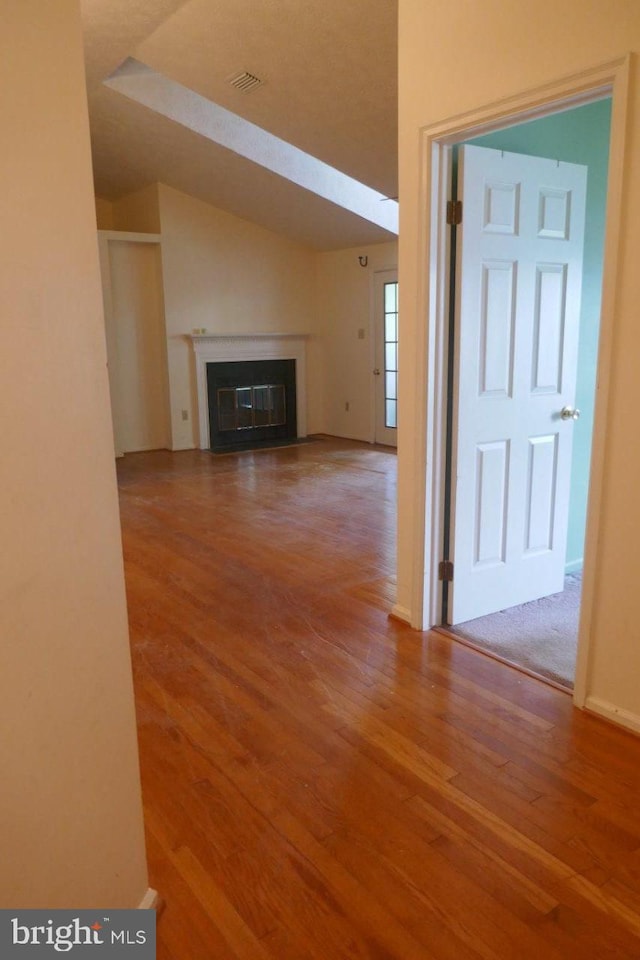 unfurnished living room featuring vaulted ceiling and hardwood / wood-style flooring