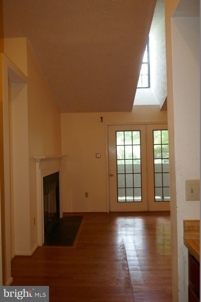 unfurnished living room featuring hardwood / wood-style flooring and a towering ceiling