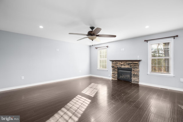 unfurnished living room featuring a fireplace, dark wood-type flooring, and ceiling fan