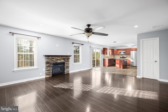 unfurnished living room with dark wood-type flooring, ceiling fan, and a fireplace