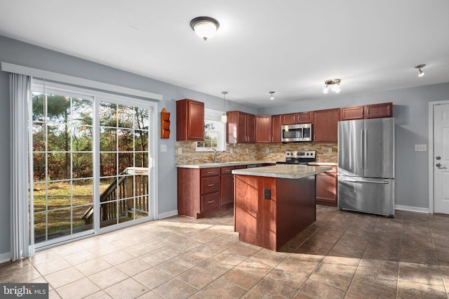 kitchen featuring stainless steel appliances, hanging light fixtures, decorative backsplash, sink, and a center island