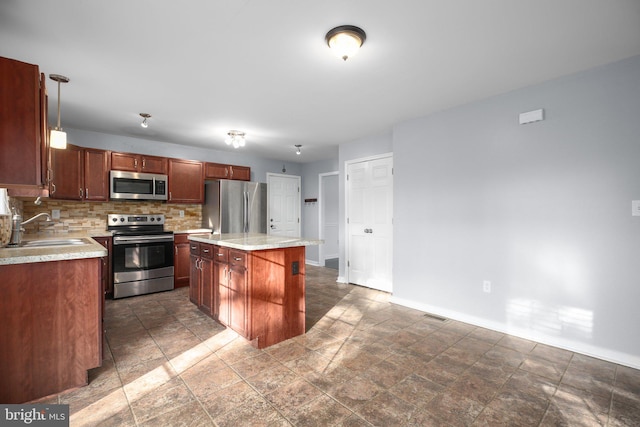 kitchen with sink, appliances with stainless steel finishes, backsplash, hanging light fixtures, and a kitchen island