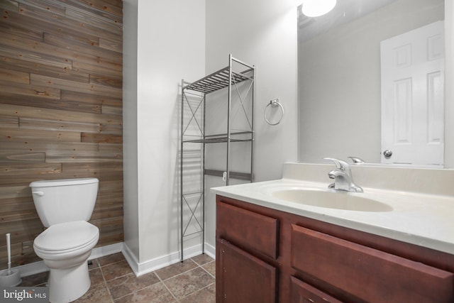 bathroom featuring vanity, wooden walls, and toilet