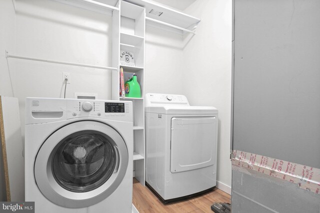 laundry room with light wood-type flooring and washer and clothes dryer