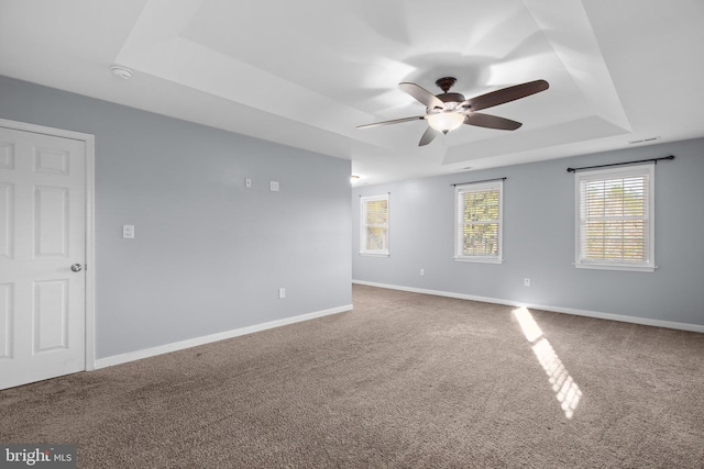 carpeted empty room with ceiling fan and a raised ceiling