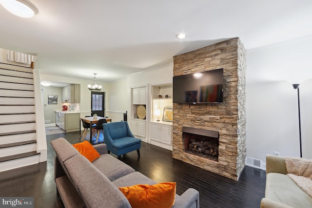 living room featuring a notable chandelier, a fireplace, crown molding, and dark hardwood / wood-style flooring