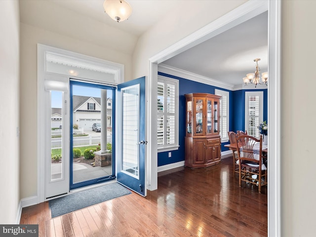 foyer entrance featuring a healthy amount of sunlight, ornamental molding, hardwood / wood-style floors, and a chandelier