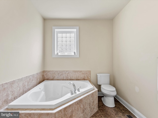 bathroom featuring tile patterned flooring, toilet, and a relaxing tiled tub