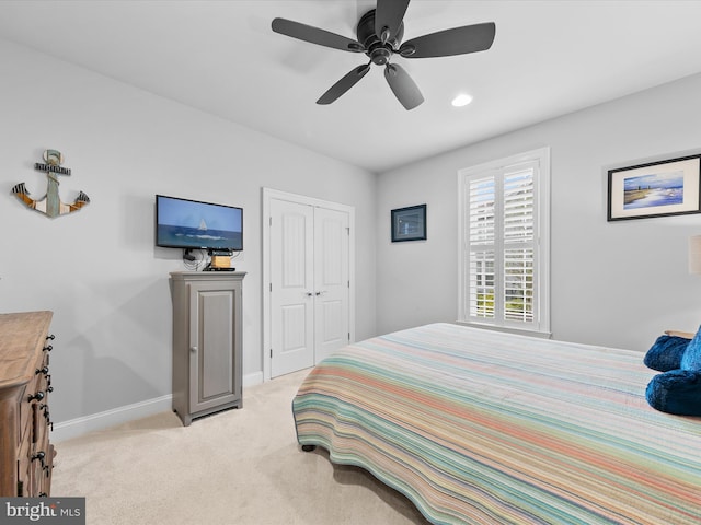 bedroom with a closet, ceiling fan, and light colored carpet