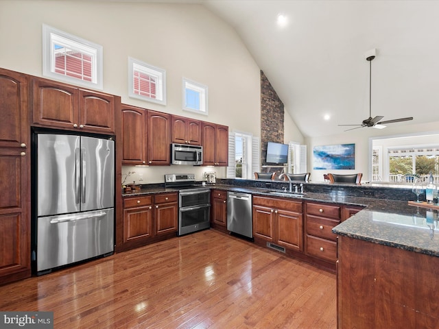 kitchen with ceiling fan, sink, wood-type flooring, high vaulted ceiling, and appliances with stainless steel finishes