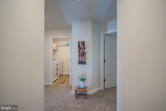 corridor with separate washer and dryer and light colored carpet