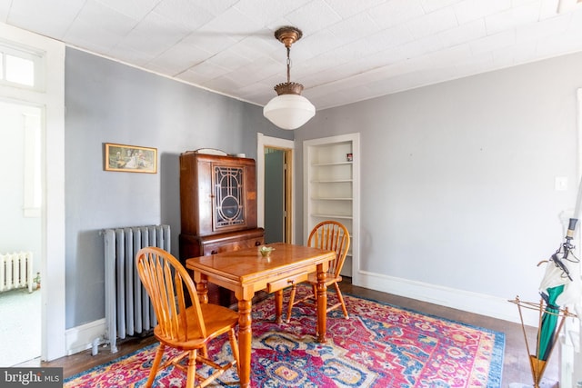 dining area with hardwood / wood-style flooring, radiator, and built in features