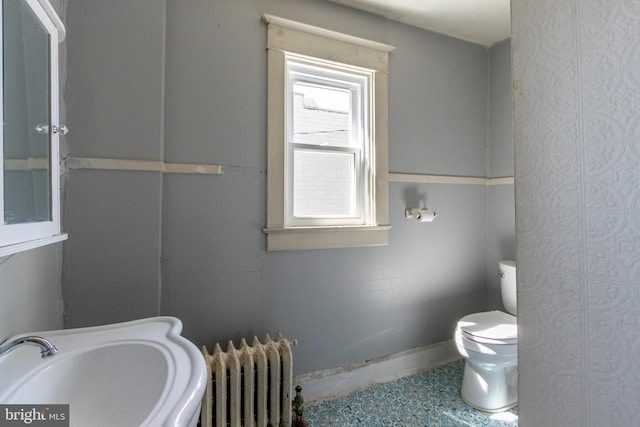 bathroom featuring radiator heating unit, toilet, sink, and tile walls