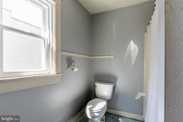 bathroom with toilet and tile walls