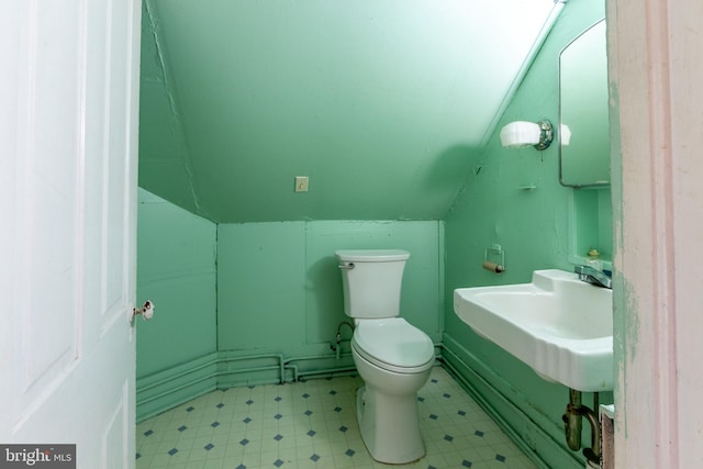 bathroom featuring lofted ceiling, toilet, and sink