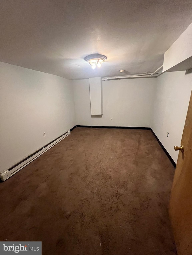 basement featuring dark carpet and baseboard heating