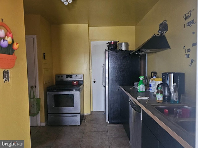 kitchen with appliances with stainless steel finishes, dark tile patterned floors, and sink