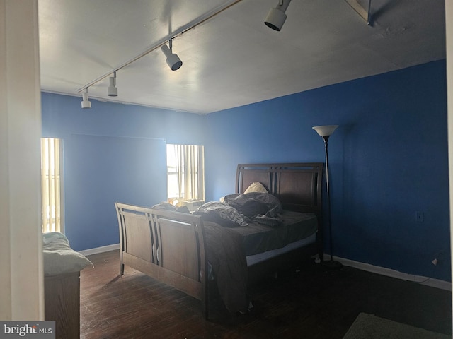 bedroom featuring track lighting and dark wood-type flooring