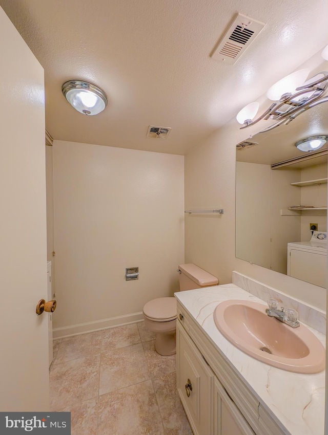 bathroom with vanity, toilet, washer / dryer, and a textured ceiling