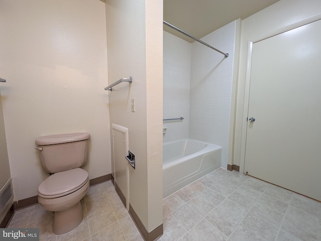 bathroom with tile patterned flooring, tiled shower / bath combo, and toilet