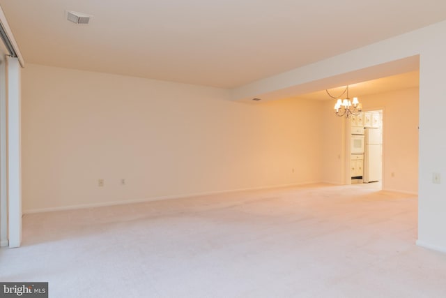 carpeted spare room featuring a chandelier