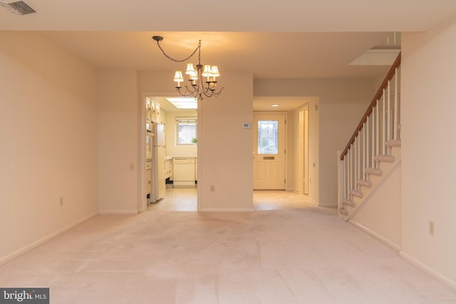 unfurnished room with light colored carpet and a notable chandelier