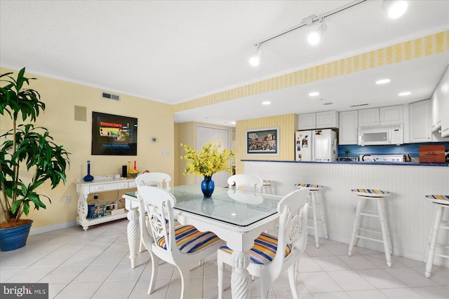 dining space featuring ornamental molding, a textured ceiling, and light tile patterned flooring