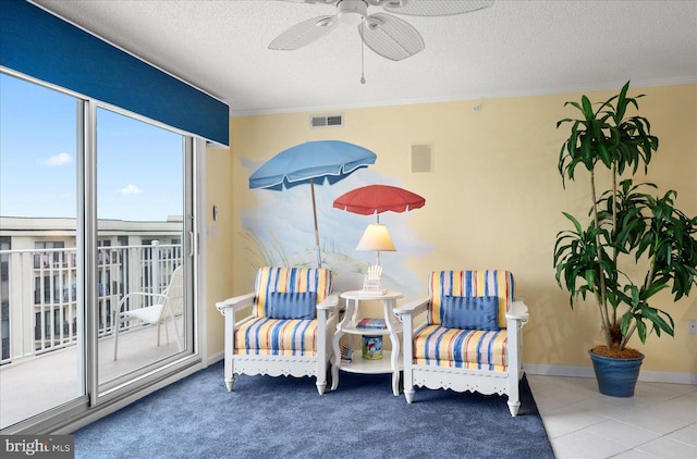 sitting room featuring ceiling fan, crown molding, tile patterned floors, and a textured ceiling