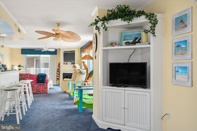 game room with ceiling fan, a textured ceiling, dark colored carpet, and ornamental molding