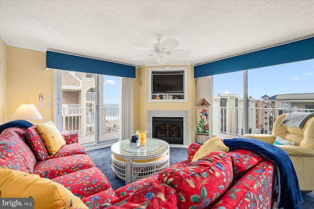 carpeted living room featuring ornamental molding, a high end fireplace, ceiling fan, and a textured ceiling