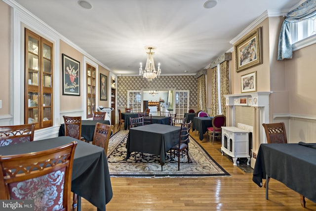 dining space featuring wood-type flooring, a notable chandelier, a fireplace, and crown molding