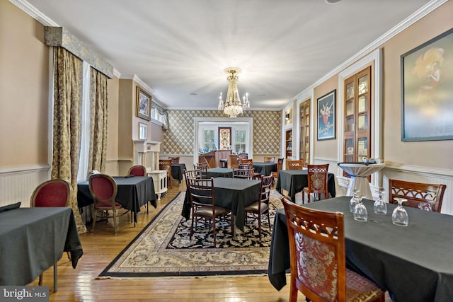 dining area featuring a notable chandelier, light wood-type flooring, and ornamental molding