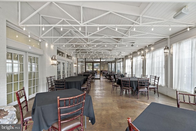 dining space with high vaulted ceiling, concrete flooring, and french doors