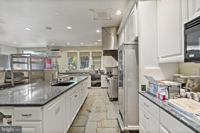 kitchen featuring dark stone counters, white cabinetry, a center island, and sink