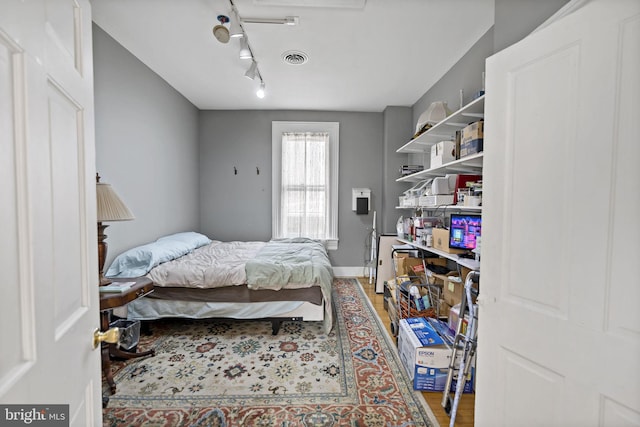 bedroom with hardwood / wood-style flooring and rail lighting