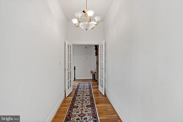 hall with a chandelier, hardwood / wood-style flooring, and french doors