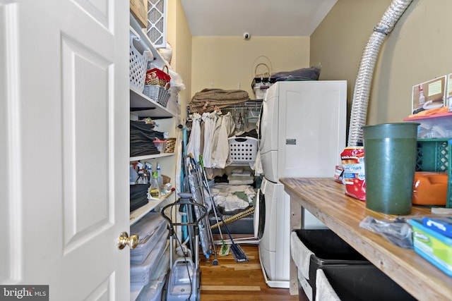 spacious closet with stacked washer / drying machine and hardwood / wood-style floors