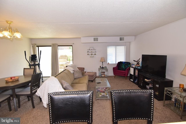 carpeted living room featuring a notable chandelier, a textured ceiling, and a wealth of natural light