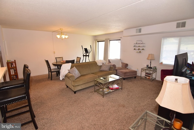 carpeted living room featuring a textured ceiling, plenty of natural light, and a chandelier