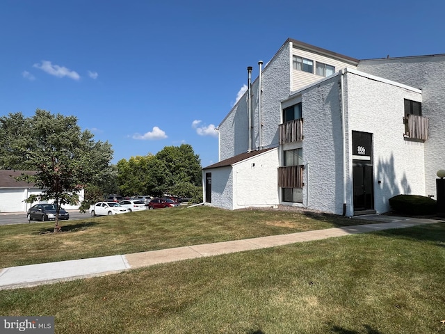 view of side of home featuring a balcony and a lawn