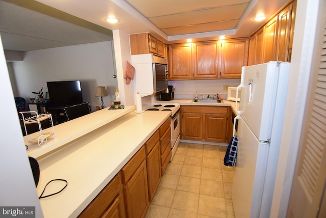 kitchen featuring white appliances, kitchen peninsula, light tile patterned floors, and sink