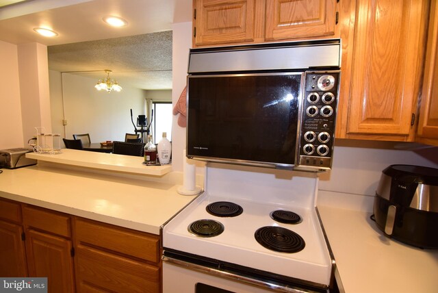 kitchen featuring a textured ceiling, hanging light fixtures, electric stove, and a chandelier