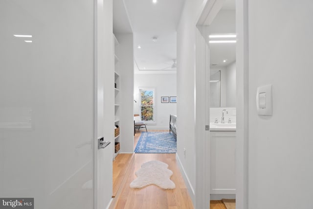 hallway with sink and light wood-type flooring