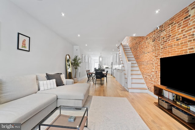 living room with light hardwood / wood-style floors and brick wall