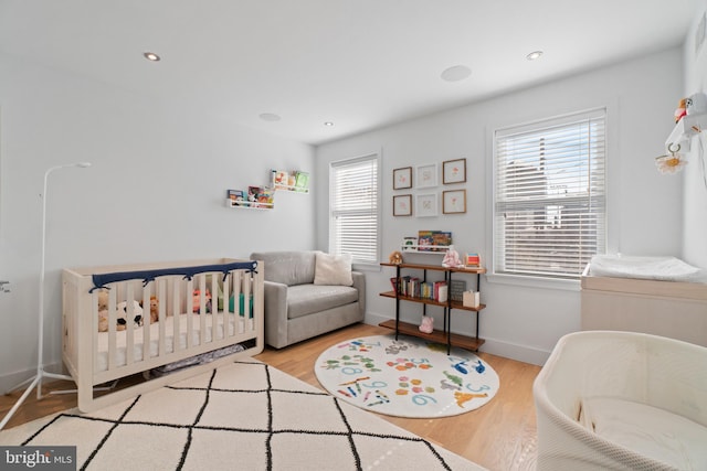 bedroom with light hardwood / wood-style floors and a crib