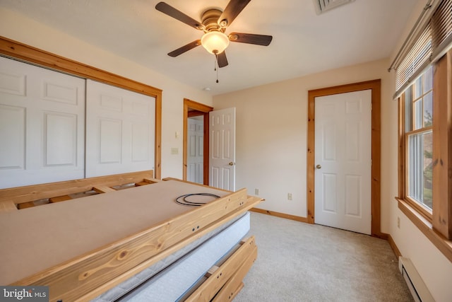 unfurnished bedroom with baseboard heating, ceiling fan, a closet, and light carpet