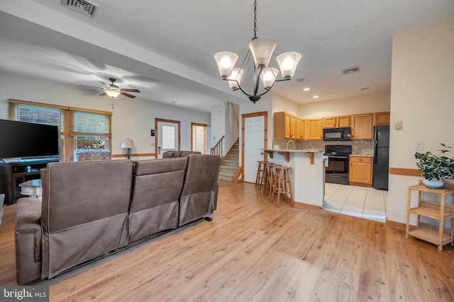 living room featuring light hardwood / wood-style flooring and ceiling fan with notable chandelier