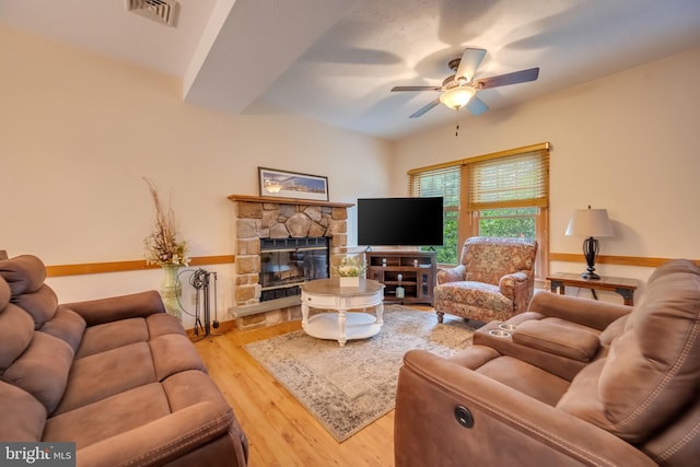 living room featuring a fireplace, light hardwood / wood-style floors, and ceiling fan